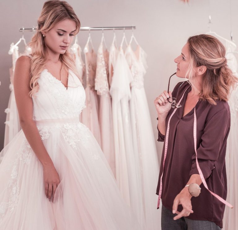 Une créatrice aide une mariée à choisir une robe de mariée dans une boutique.